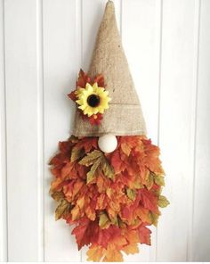 a door hanger decorated with fall leaves and a gnome's hat on it