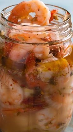 a jar filled with shrimp and vegetables on top of a table