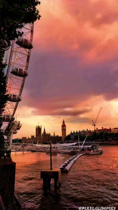 a ferris wheel sitting on top of a river under a cloudy sky