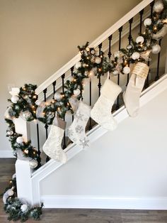 christmas stockings hanging on the banister and stairs decorated with lights, garlands and snowflakes