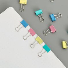 several binders and clips are arranged on top of a notepad, next to each other