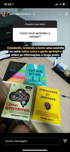 a table with some books on it and a person holding a cell phone in front of them