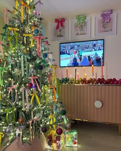 a decorated christmas tree in front of a flat screen tv with colorful ribbons on it