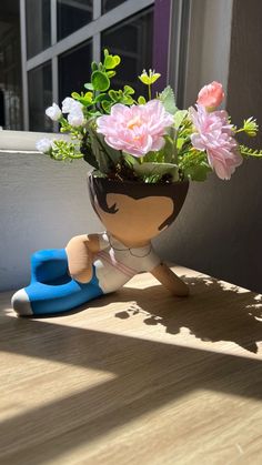 a potted plant sitting on top of a wooden table next to a pair of blue shoes