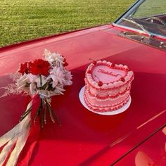 a pink cake sitting on top of a red car