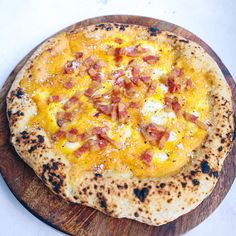 a pizza with cheese and bacon on a wooden board