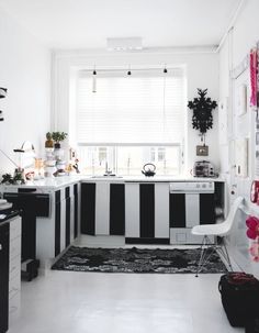 a black and white kitchen with lots of clutter on the counter top, along with an area rug