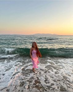 a woman standing in the ocean at sunset