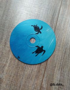 a blue disc with two turtles on it sitting on top of a wooden table next to a bottle opener