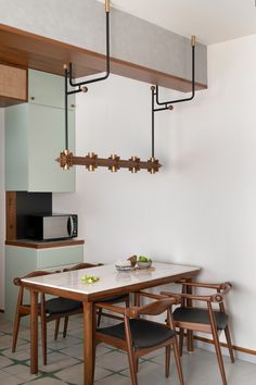 a dining table and chairs in a room with white walls, green tile flooring and wooden beams