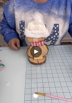 a woman is making an ornament out of wood and paper with her hands