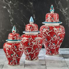 three red vases with blue and white designs sit on a marble floor next to each other