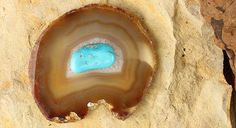 a piece of agate stone with a blue substance in it's center sitting on some rocks