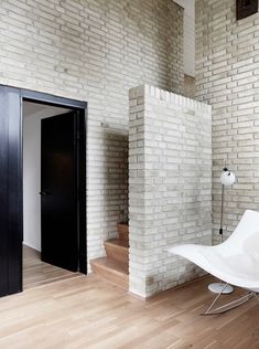 a white chair sitting on top of a hard wood floor next to a doorway and door