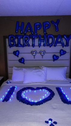 a bed decorated with blue lights and the words happy birthday spelled out in the shape of a heart