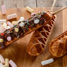 two waffles with chocolate frosting and sprinkles are on a cutting board