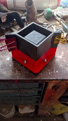 a red and black box sitting on top of a wooden table next to other tools