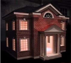 a doll house is lit up at night with the lights on and windows open in front of it