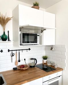 a kitchen with white cabinets and wooden counter tops, including a microwave above the stove