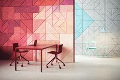 two chairs and a table in front of a wall with geometric designs on it,