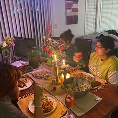 people sitting at a table with food and candles