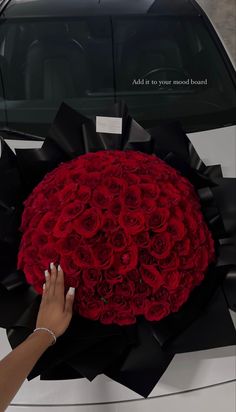 a woman's hand is holding a large bouquet of roses in front of a car