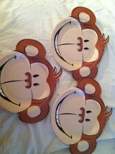 three paper plates with monkeys on them sitting on a white sheet covered bed in the shape of faces