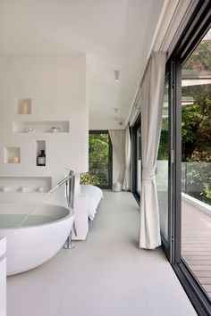 there is a large white bathtub in the bathroom with glass doors leading to another room