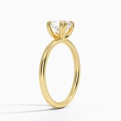 a yellow gold engagement ring with a pear shaped diamond in the center, on a white background