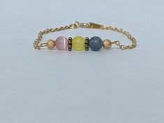 Bracelet designed in the colors of the Pansexual PRIDE flag. This flag is available in 2 patterns. All patterns are nickel and plastic free.  Pattern 1: Gold plated brass chain. The gemstones used are: 6mm pink cats-eye, 6mm yellow glass, 6mm blue aventurine. The accents used are 6mm metal flower spacers an gold star dusted crimp covers.  Pattern 2: Silver plated brass chain. The gemstones used are: 6mm rose quartz, 6 mm yellow glass, 6mm blue aventurine. The accents are black seed beads.  This Flag Bracelet, Pansexual Flag, Blue Aventurine, Pansexual Pride, Bracelets Design, Black Seed, Cats Eye, Star Bracelet, Pink Cat