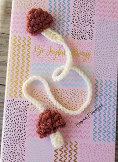 a crocheted bookmark with two pom - poms attached to it