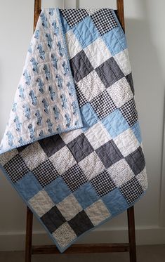 a blue and black quilt sitting on top of a wooden chair next to a white wall