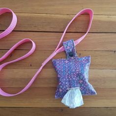 a purple and white bag with a pink lanyard on it sitting on top of a wooden floor