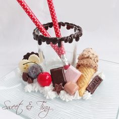 an ice cream sundae with candy, candies and strawberries in it on a glass plate