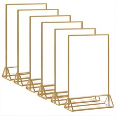 four gold metal frames with white paper on them