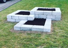 an outdoor fire pit made out of cinder blocks and black dirt in the middle of grass