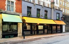 an empty street in front of some buildings with yellow awnings on the windows