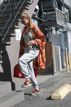 a woman is walking down the street with an orange and white checkered coat on