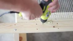 a person using a power drill to attach pegs on a piece of plywood