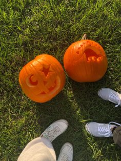 three carved pumpkins sitting in the grass with their faces carved like jack - o'- lanterns