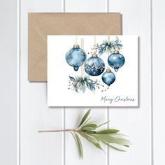 a christmas card with blue ornaments hanging from it