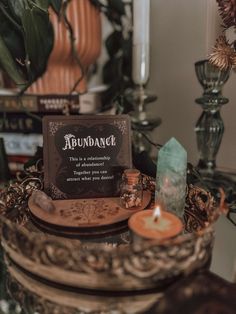 a table topped with candles and a sign that reads abundance next to a potted plant