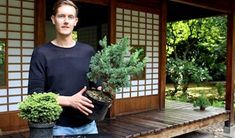 a man standing in front of a house holding a potted plant