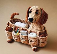 a crocheted dog sitting in a basket with scissors and other items inside it