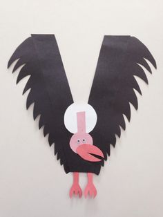 a black and pink bird made out of paper on a white background with the letter v cut out