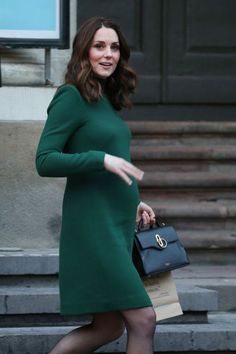 a woman in a green dress is walking down the street with her hand on her hip