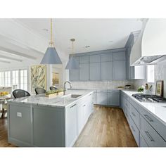 a large kitchen with an island in the middle and two pendant lights hanging from the ceiling