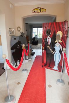 a red carpeted entrance way leading to a room with paintings on the walls and floor