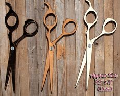 three pairs of scissors sitting on top of a wooden table