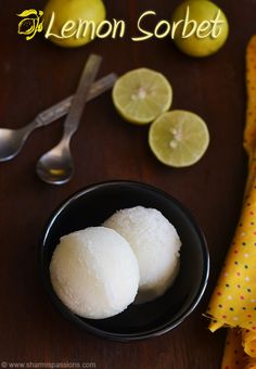 two lemon sorbet in a black bowl next to sliced lemons